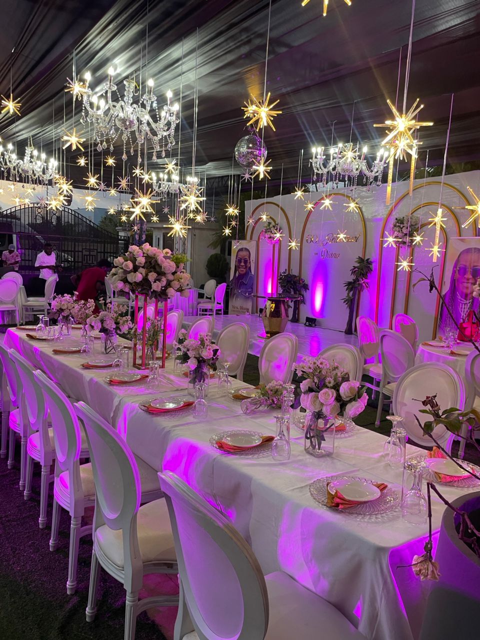 Elegant dinner setup with chandeliers and pink ambient lighting